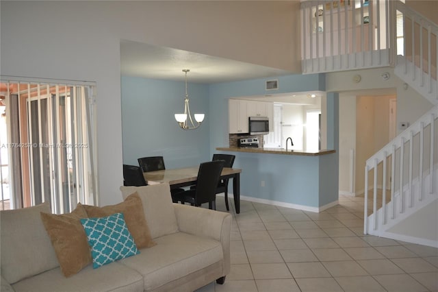 living room featuring stairway, baseboards, visible vents, light tile patterned flooring, and a towering ceiling