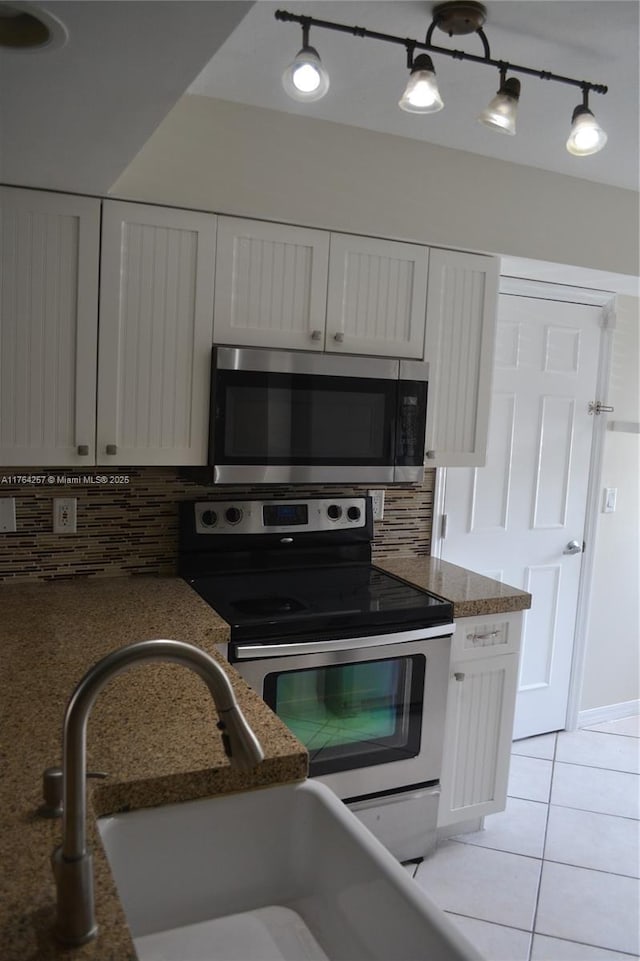 kitchen featuring light tile patterned flooring, decorative backsplash, appliances with stainless steel finishes, and white cabinetry