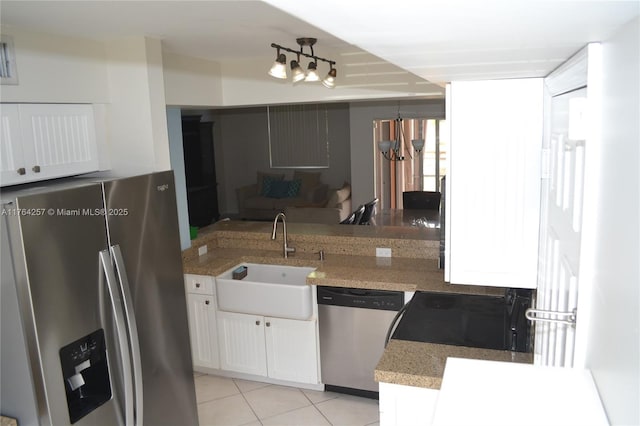 kitchen featuring light stone counters, light tile patterned floors, a sink, appliances with stainless steel finishes, and white cabinetry