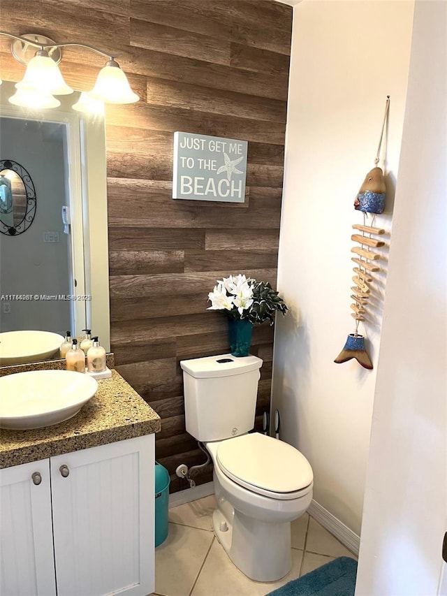 half bathroom featuring tile patterned floors, toilet, wood walls, and vanity