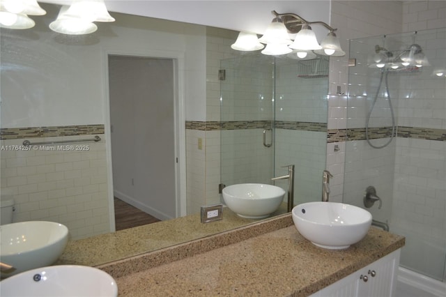 full bath featuring a tile shower, vanity, and tile walls