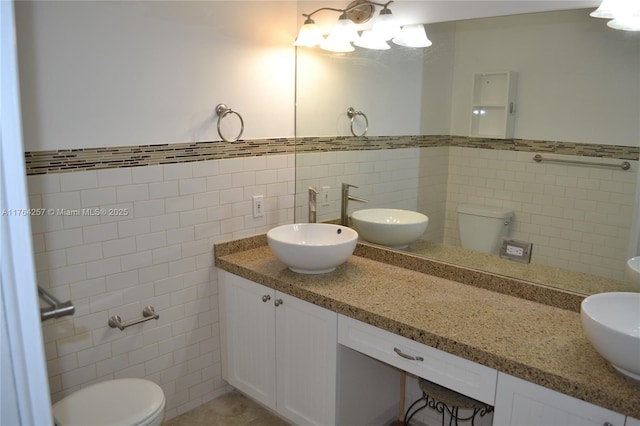 bathroom with toilet, tile walls, and vanity