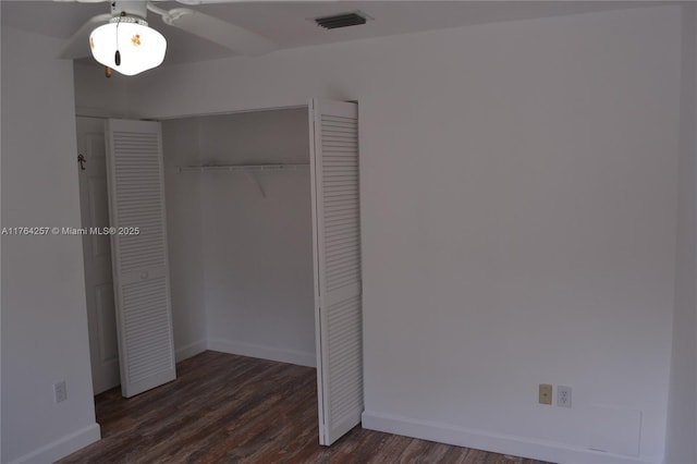 unfurnished bedroom featuring a closet, visible vents, dark wood finished floors, and baseboards