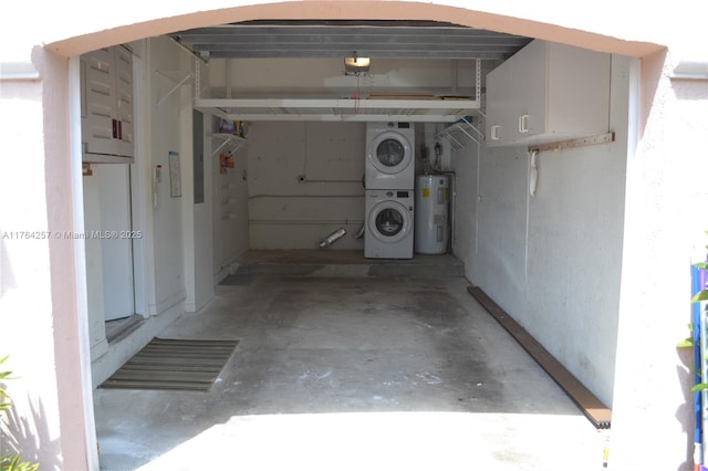 garage with electric water heater and stacked washer / drying machine