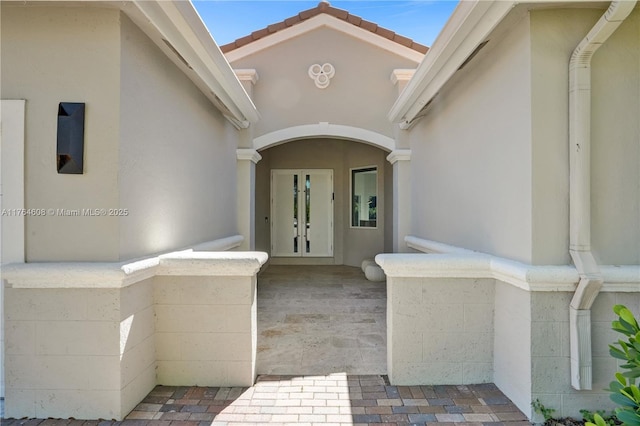 entrance to property featuring stucco siding and french doors