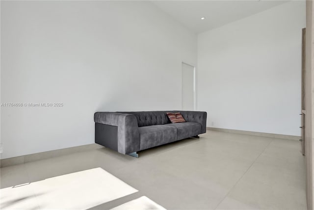 sitting room with baseboards and a high ceiling