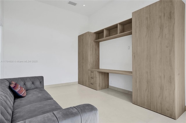 living area with visible vents, built in study area, baseboards, and finished concrete flooring