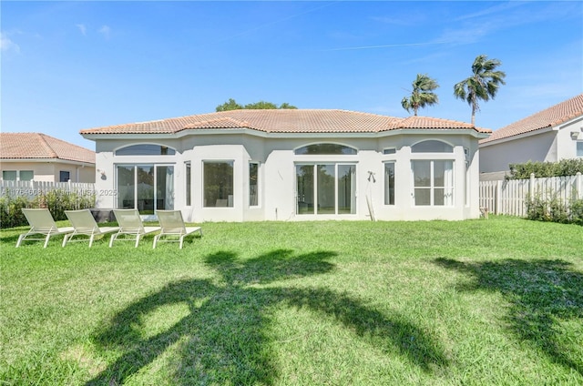 back of property featuring a yard, fence, stucco siding, and a tiled roof