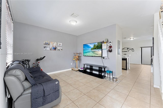 living room with light tile patterned floors, visible vents, and baseboards