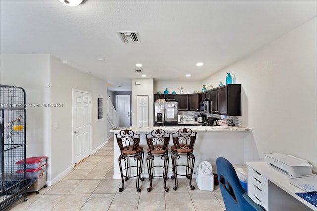 kitchen with visible vents, backsplash, a breakfast bar, light countertops, and stainless steel appliances