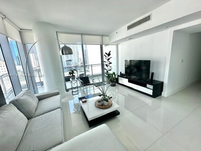 living room featuring a wealth of natural light, visible vents, floor to ceiling windows, and baseboards