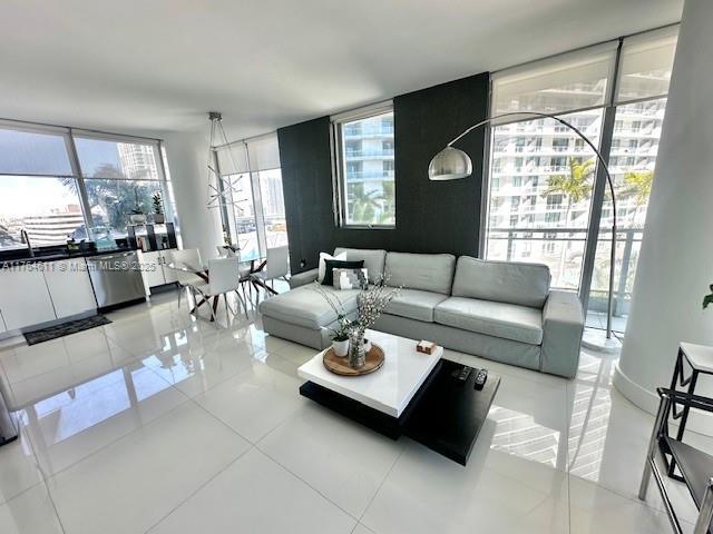 living room featuring a wall of windows and light tile patterned floors