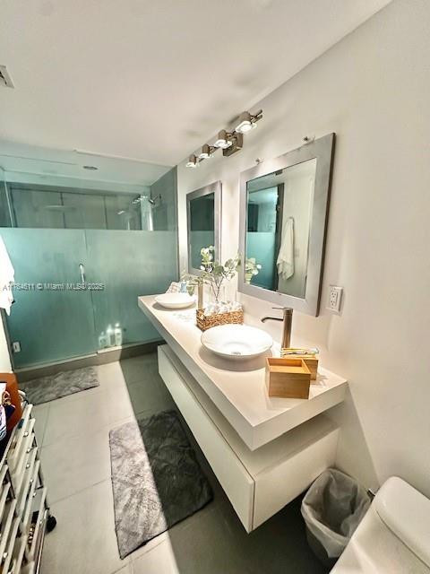 full bath with tile patterned floors, toilet, a sink, a shower stall, and double vanity