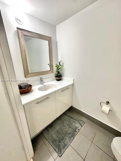 bathroom with tile patterned flooring, toilet, vanity, and baseboards