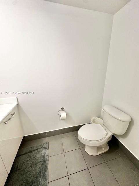 bathroom with tile patterned floors, baseboards, toilet, and vanity