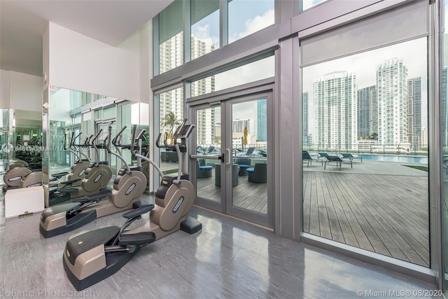 gym with wood finished floors and a towering ceiling