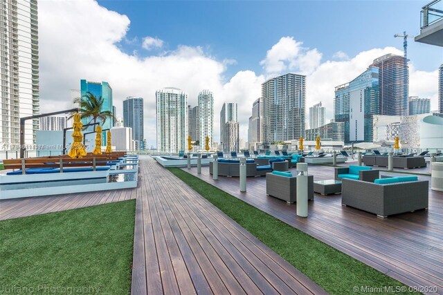 wooden deck with an outdoor living space, a lawn, and a city view