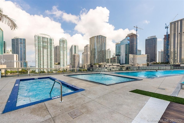 community pool with a patio and a city view