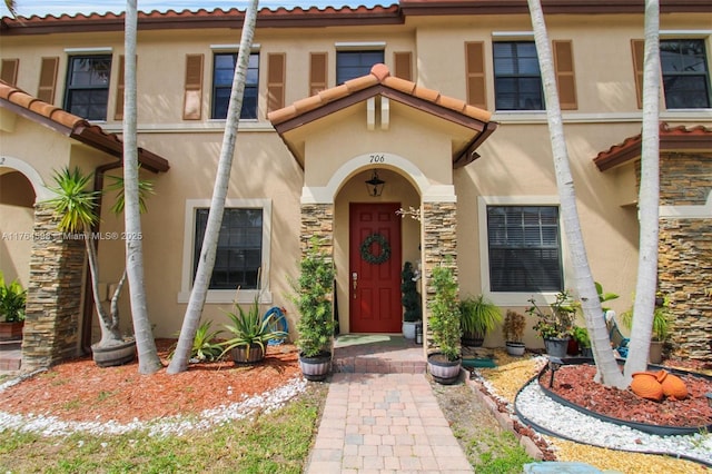 doorway to property featuring stone siding and stucco siding