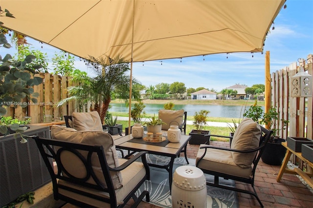 view of patio featuring outdoor lounge area, fence, and a water view