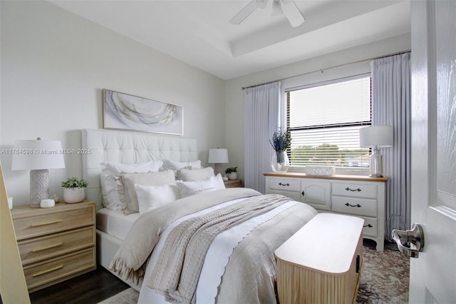 bedroom featuring dark wood finished floors, a raised ceiling, and a ceiling fan