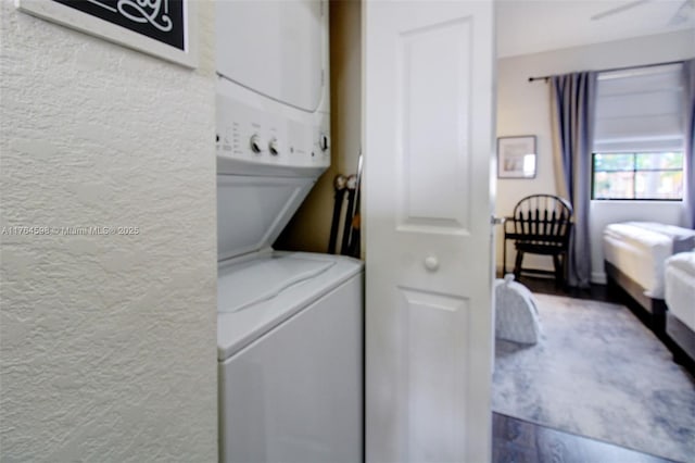 laundry room featuring a textured wall, laundry area, and stacked washer / dryer