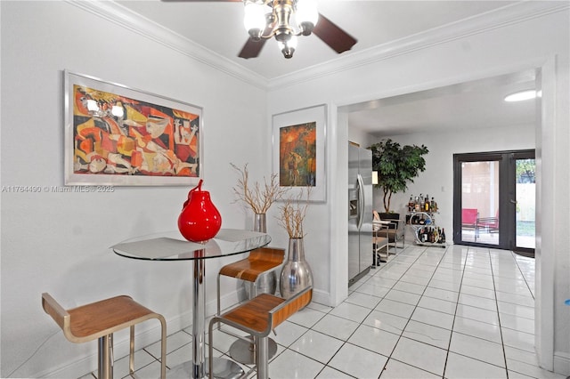 dining area featuring light tile patterned flooring, a ceiling fan, baseboards, and ornamental molding