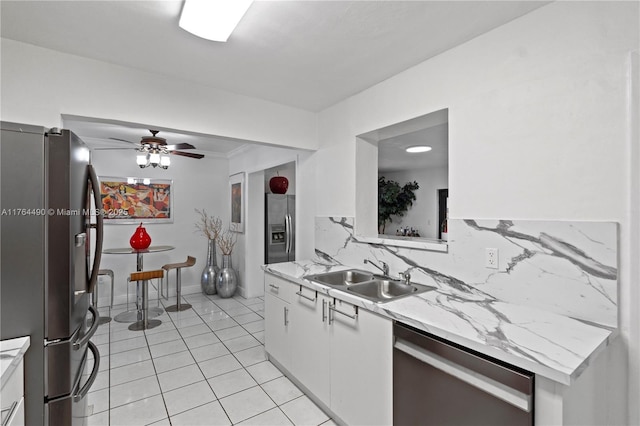 kitchen featuring ceiling fan, a sink, appliances with stainless steel finishes, white cabinetry, and backsplash