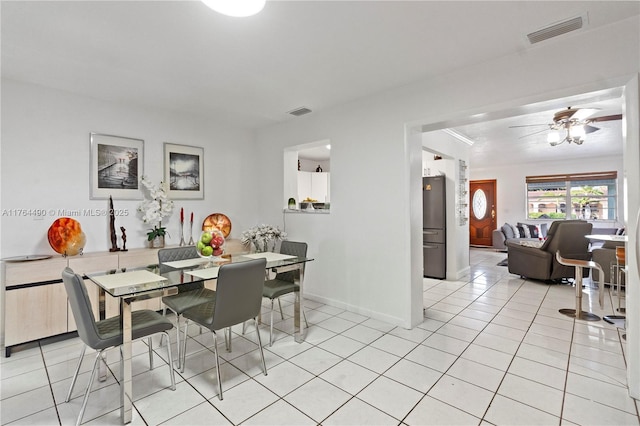 dining space featuring light tile patterned flooring, a ceiling fan, visible vents, and baseboards