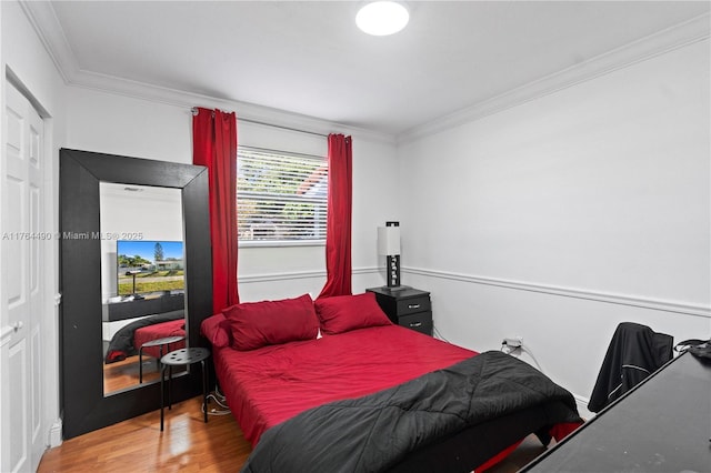 bedroom with wood finished floors and ornamental molding