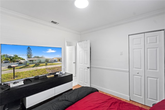 bedroom with baseboards, wood finished floors, visible vents, and ornamental molding