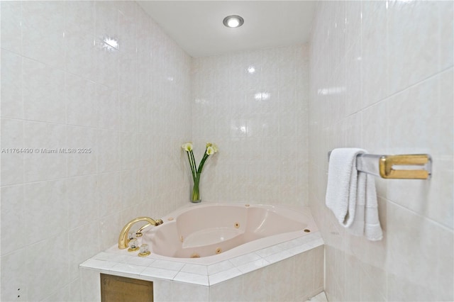 bathroom with a tub with jets and tile walls