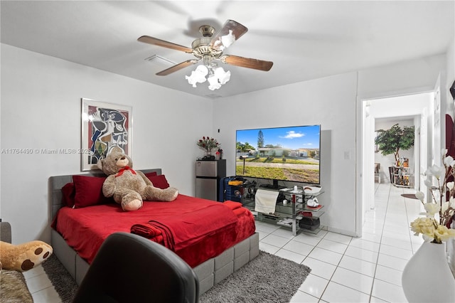 bedroom featuring light tile patterned floors, freestanding refrigerator, and ceiling fan