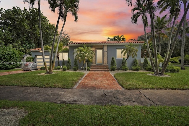 mediterranean / spanish-style home with a tile roof, a front lawn, and stucco siding