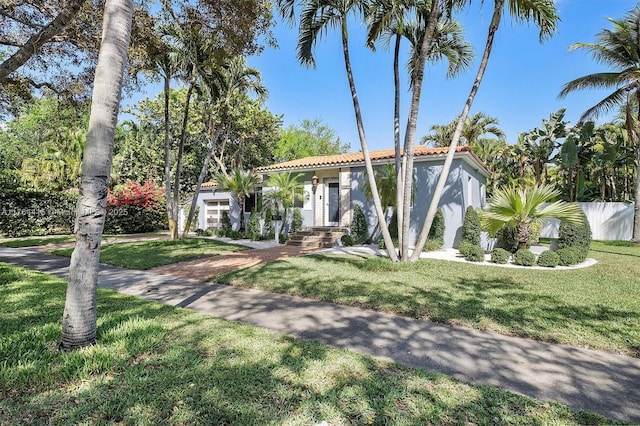 mediterranean / spanish home with stucco siding, a tiled roof, and a front yard