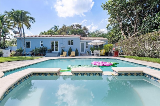 view of swimming pool featuring a patio area, french doors, a pool with connected hot tub, and entry steps