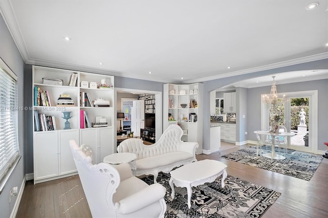 living room with wood finished floors, recessed lighting, arched walkways, crown molding, and a notable chandelier