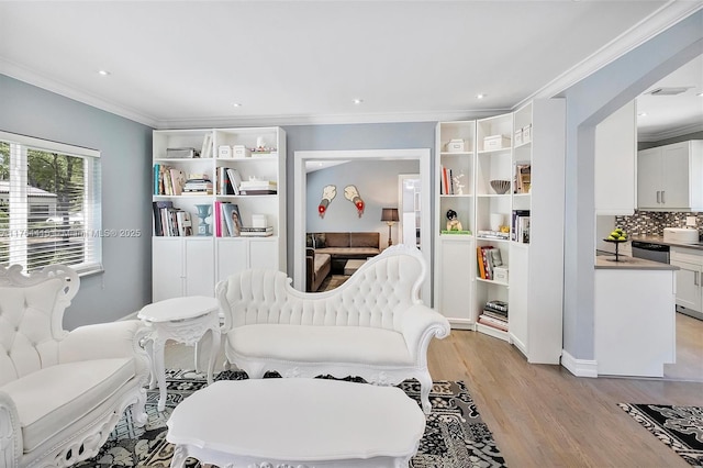 sitting room featuring recessed lighting, crown molding, and light wood-style floors