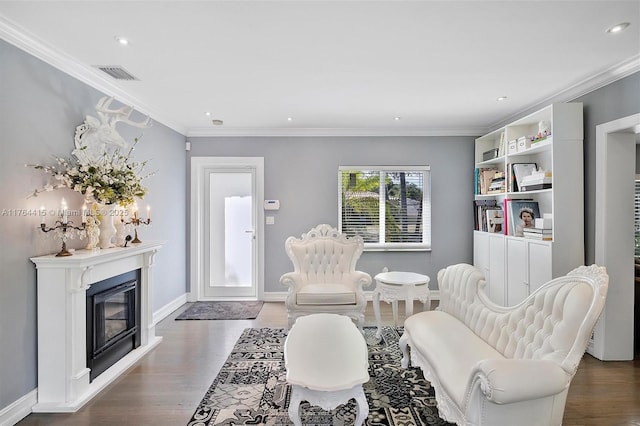 living area featuring visible vents, baseboards, wood finished floors, and crown molding