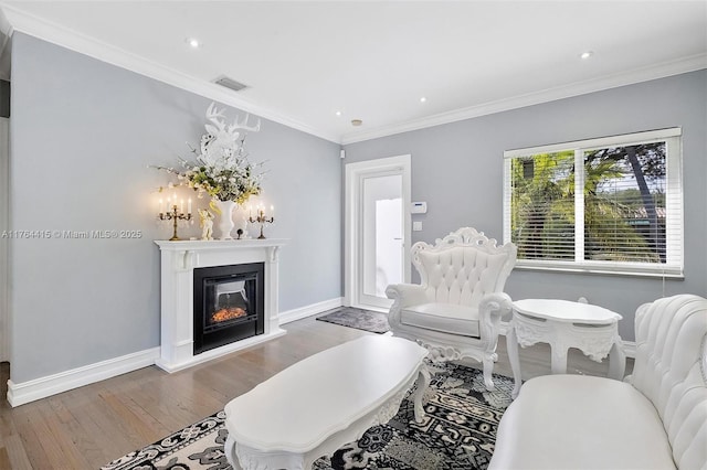 living area featuring visible vents, crown molding, baseboards, and wood finished floors