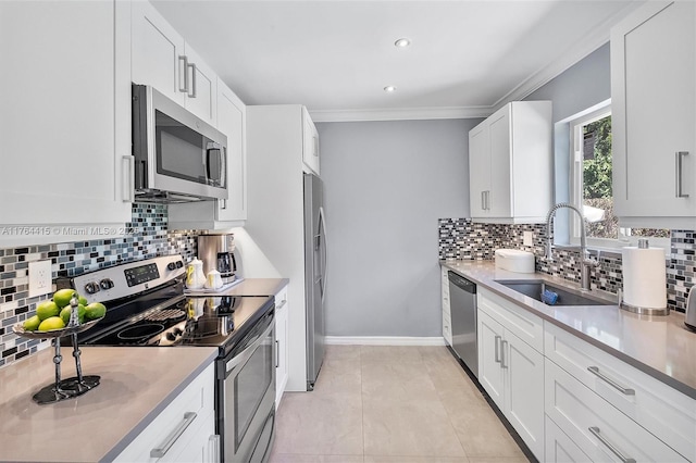 kitchen with a sink, stainless steel appliances, white cabinetry, crown molding, and tasteful backsplash