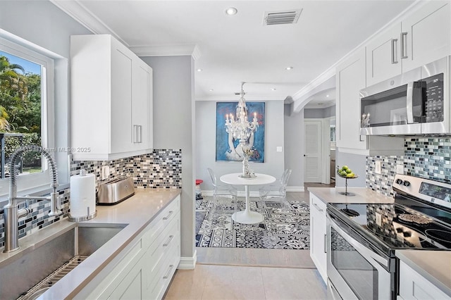 kitchen with visible vents, a notable chandelier, a sink, stainless steel appliances, and crown molding