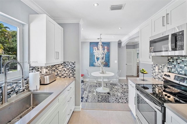 9301 NW 2nd Pl, Miami Shores, FL 33150 - kitchen with stainless steel appliances, a sink, crown molding, a chandelier, and white cabinets