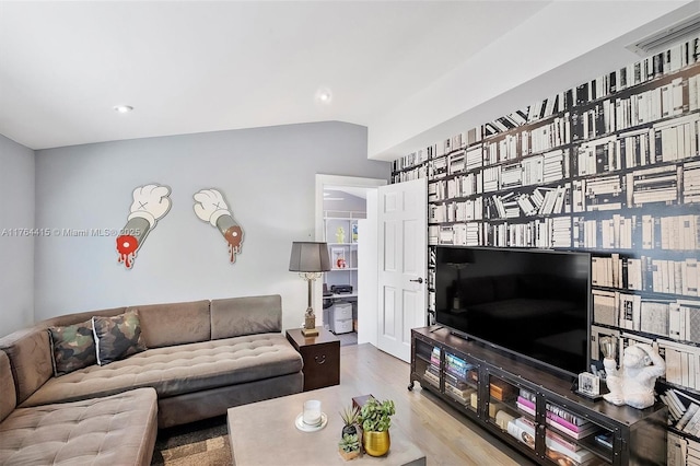 living area featuring visible vents, wood finished floors, and vaulted ceiling