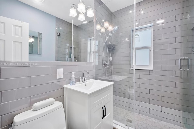 full bath featuring a shower stall, toilet, vanity, a notable chandelier, and tile walls