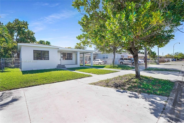 view of front of house featuring an attached carport, a front yard, fence, and stucco siding