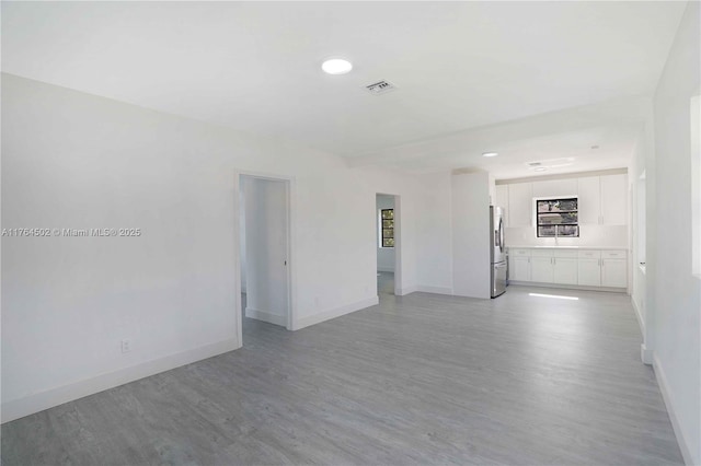 unfurnished room featuring visible vents, baseboards, and light wood finished floors