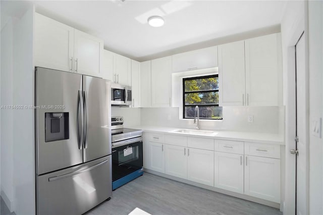 kitchen with a sink, light countertops, white cabinets, and stainless steel appliances