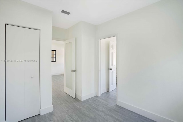 empty room with wood finished floors, visible vents, and baseboards