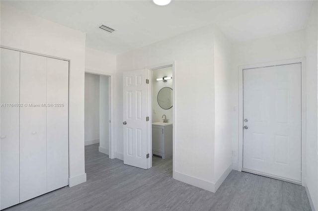 interior space featuring visible vents, a sink, baseboards, and wood finished floors